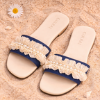 Pair of blue sandals with lace straps on a sandy surface.
