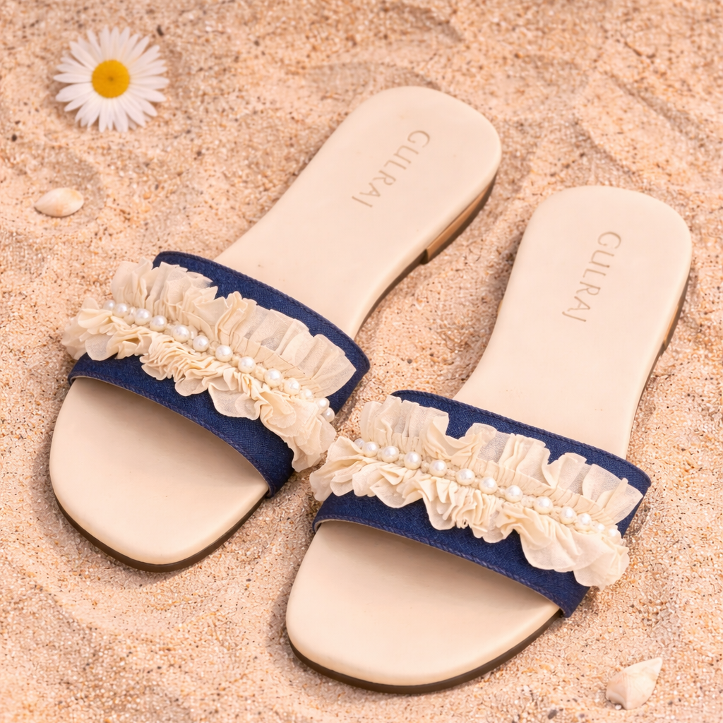 Pair of blue sandals with lace straps on a sandy surface.