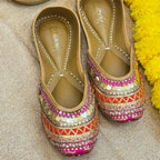 Decorative shoes with colorful patterns on a textured surface with yellow flowers and a metallic object.